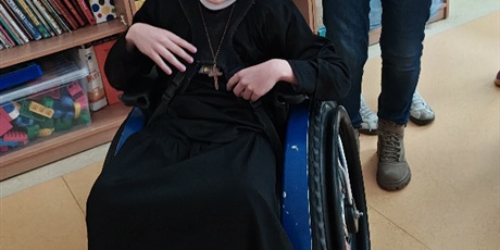 Powiększ grafikę: Chłopiec na wózku przebrany w strój księdza.