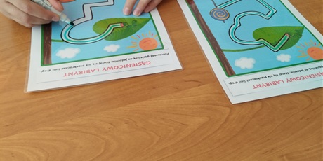 Powiększ grafikę: Na stoliku leżą dwie kartki z labiryntem w kształcie gąsiennicy.