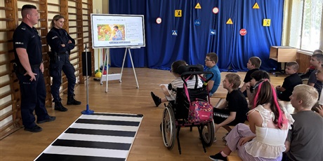 Powiększ grafikę: Policjant i policjantka wyjaśniają co znajduje się na slajdach w prezentacji.