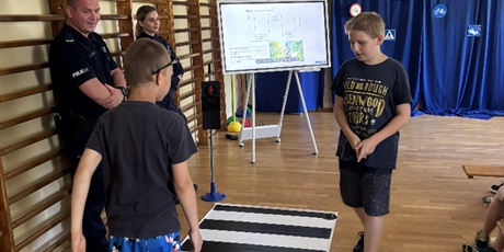 Powiększ grafikę: Uczniowie prezentują jak prawidłowo należy przechodzić przez przejście.