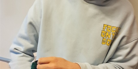 Powiększ grafikę: Chłopiec stoi, trzyma rękę w zielonym worku w piłki.