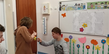 Powiększ grafikę: Chłopiec wręcza dziewczynce kwiatek.