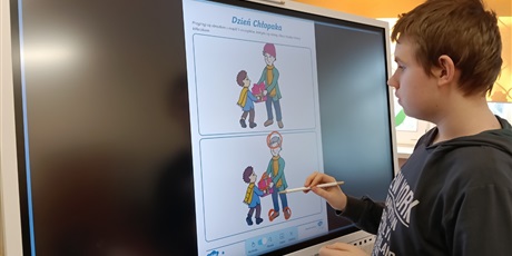 Powiększ grafikę: Chłopiec zaznacza różnice między obrazkami na tablicy multimedialnej.