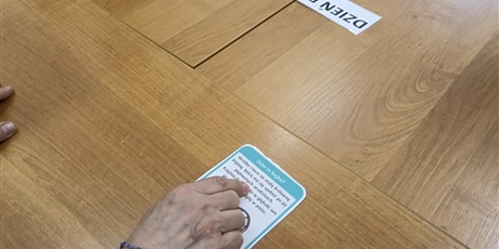 Powiększ grafikę: Na stole leży karta z opisem księżniczki, widać dłoń i palec wskazujący leżący na karcie.