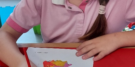 Powiększ grafikę: Dziewczynka maluje farbami rysunek sowy.