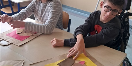 Powiększ grafikę: Dziewczynka i chłopiec siedzą przy stoliku, wyklejają pieska z kółek.