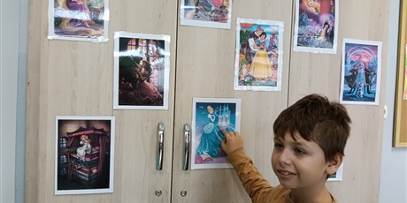 Powiększ grafikę: Chłopiec pokazuje zdjęcie przyklejone na szafie w klasie.