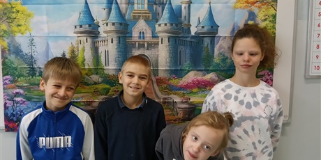 Powiększ grafikę: Dwie dziewczynki i dwóch chłopców stoją na tle plakaty z baśniowym zamkiem.