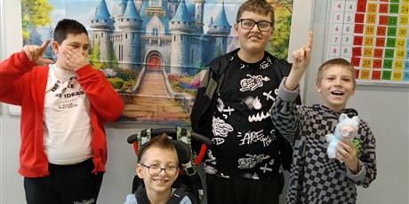 Powiększ grafikę: Czterech chłopców- jeden na wózku - stoją na tle plakatu z baśniowym zamkiem.