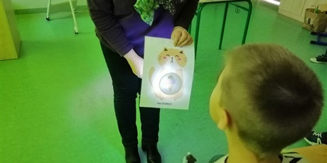Powiększ grafikę: Nauczyciel pokazuje chłopcu zdjęcie z kotem.