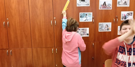 Powiększ grafikę: Dziewczynka przykleja na szafie szablon ołówka z papieru.