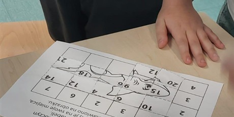 Powiększ grafikę: Na stolku leży układanka puzzle matematyczne.