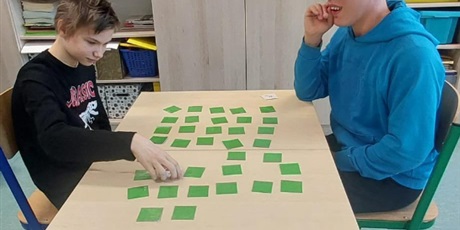 Powiększ grafikę: Dwóch uczniów siedzi przy stoliku, graja w memo matematyczne.