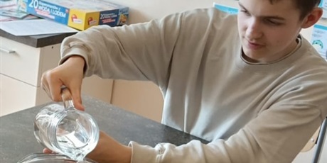 Powiększ grafikę: Chłopiec nalewa wodę z dzbanka do miski.