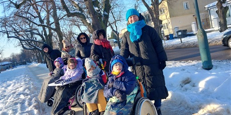 Powiększ grafikę: Uczniowie na wózkach i panie opiekunki stoją w rzędzie na ścieżce zasypanej śniegiem.
