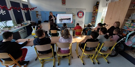 Powiększ grafikę: Uczniowie siedzą w sali, oglądają prezentację o bezpieczeństwie.