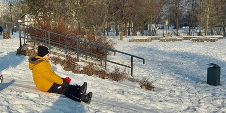 Powiększ grafikę: Chłopiec zje zjeżdża na jabłuszku z górki.