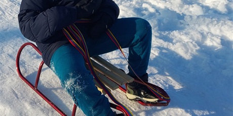 Powiększ grafikę: Chłopiec zjeżdża na sankach z górki.