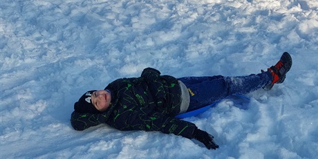 Powiększ grafikę: Chłopiec roi orła na śniegu.