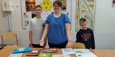 Powiększ grafikę: Uczniowie stoją przy stoliku, na którym leżą wykonane książki.