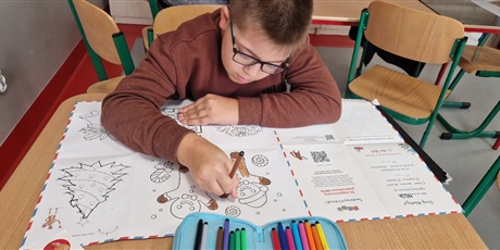 Powiększ grafikę: Chłopiec koloruje rysunek.