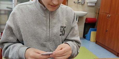 Powiększ grafikę: Chłopiec siedzi przy stoliku, rozkłada piktogramy.