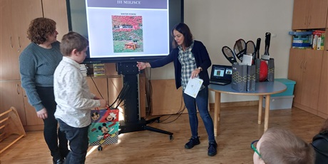 Powiększ grafikę: Chłopiec i dwie panie nauczycielki przed tablicą multimedialną, na której wyświetlane jest zdjęcie, które zrobił chłopiec.