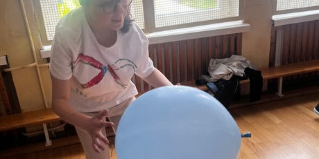 Powiększ grafikę: Dziewczynka łapie niebieskigo balona w sali gimnastycznej.