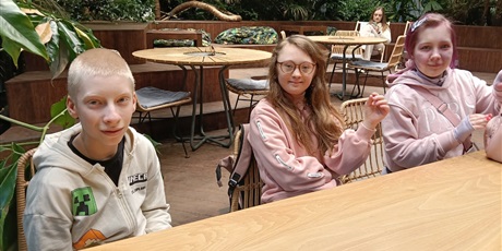 Powiększ grafikę: Troje uczniów siedzi przy stoliku.