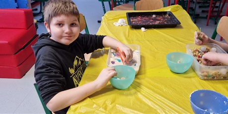 Powiększ grafikę: Uczniowie wyjmują za pomocą szczypczyków elementy z różnych mas plastycznych.