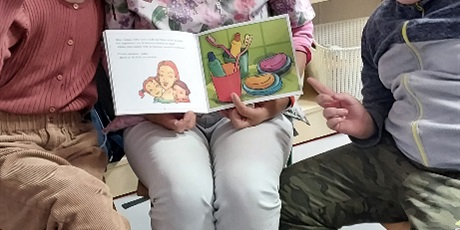 Powiększ grafikę: Dzieci siedzą dookoła pani pielęgniarki, która trzyma otwartą książkę.