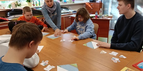 Powiększ grafikę: Ucnioie siedza przy stole, składają obrazki z części.