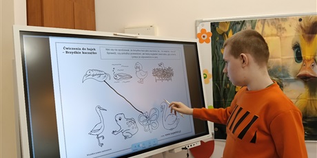 Powiększ grafikę: Chłopiec wykonuje zadanie na tablicy multimedialnej.
