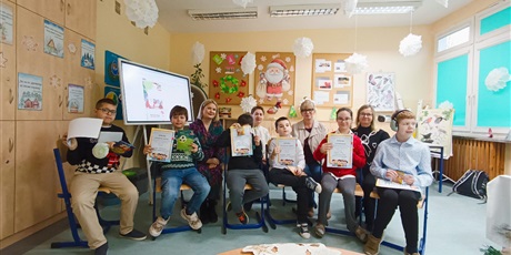 Powiększ grafikę: Grupa młodszych uczniów wraz z nauczycielami na tle świątecznej dekoracji.