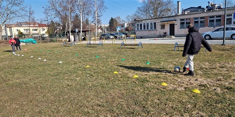 Powiększ grafikę: Chłopiec chodzi między pachołkami na boisku szkolnym.