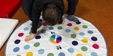 Powiększ grafikę: Chłopiec stoi na macie z kolorowymi kółkami.