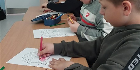 Powiększ grafikę: Chłopcy siedzą przy stoliku i kolorują obrazki.