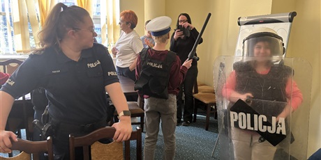 Powiększ grafikę: Uczniowie przymierzają akcesoria policyjne, obok stoi pani policjantka.