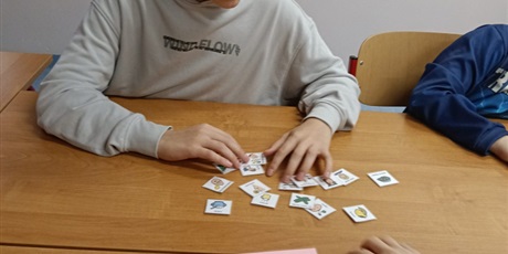 Powiększ grafikę: Uczeń ogląda leżące na stole piktogramy.