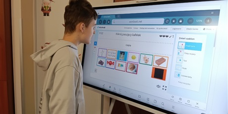 Powiększ grafikę: Chłopiec rozwiązuje zadanie na tablicy multimedialnej.