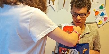 Powiększ grafikę: Dziewczynka daje torebkę prezentową chłopcu.