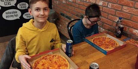 Powiększ grafikę: Dwóch chłopców siedzi przy stoliku, przed każdym leży pizza.