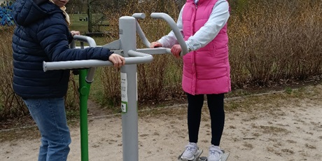 Powiększ grafikę: Uczniowie korzystają ze sprzętu na siłowni pod chmurką.