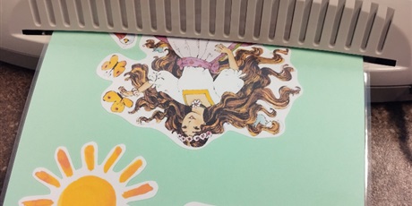 Powiększ grafikę: Zielona kartka z naklejonym słoneczkiem i panią Wiosną wychodzi z laminarki.