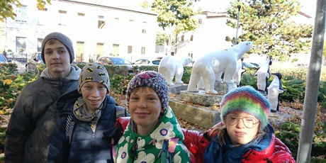 Powiększ grafikę: Czworo uczniów stoi na tle figur niedźwiedzi polarnych.