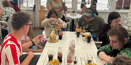 Powiększ grafikę: Uczniowie siedzą w restauracji.