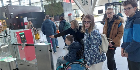 Powiększ grafikę: Uczniowie stoją przy bramkach na lotnisku.