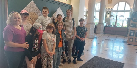 Powiększ grafikę: Siedmioro uczniów wraz z nauczycielami stoi w holu NBP w Gdańsku.