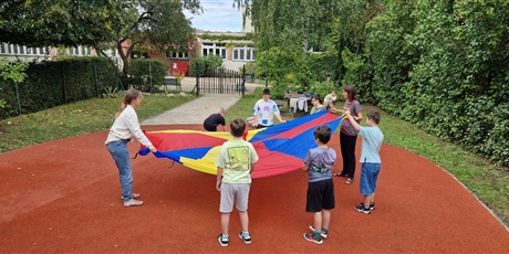 Powiększ grafikę: Uczniowie stoją w kole, trzymają za rogi chustę animacyjną.