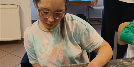 Powiększ grafikę: Dziewczynka siedziprzy stole i ozdabia pierniki.